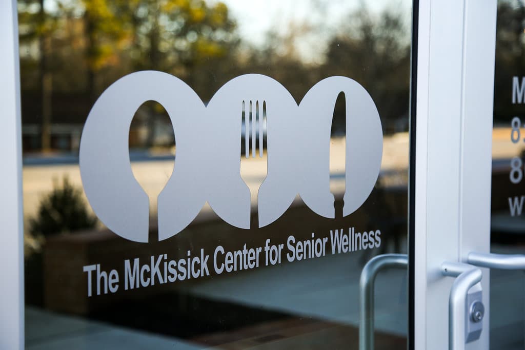 A volunteer hands a hot meal to a senior at her doorstep
